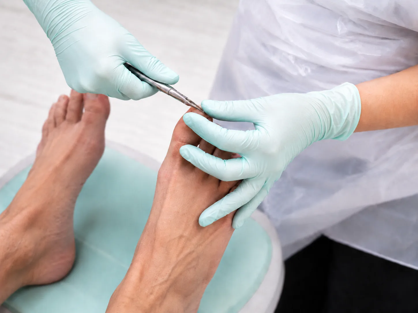 Pedicure knipt en verzorgt de teennagel van een cliënt met een nageltang.